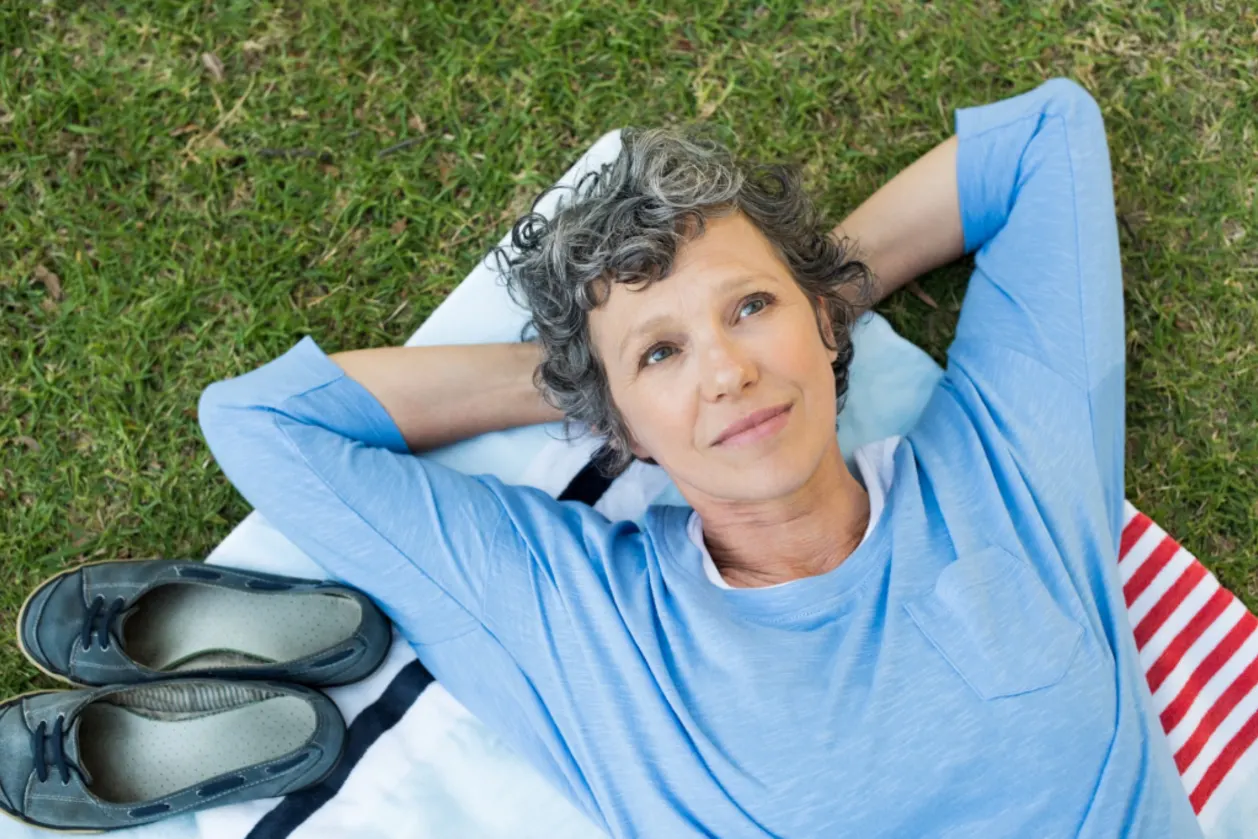 Mature woman laying down on grass in park